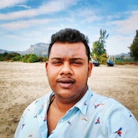 a man in a blue shirt standing on a sandy beach